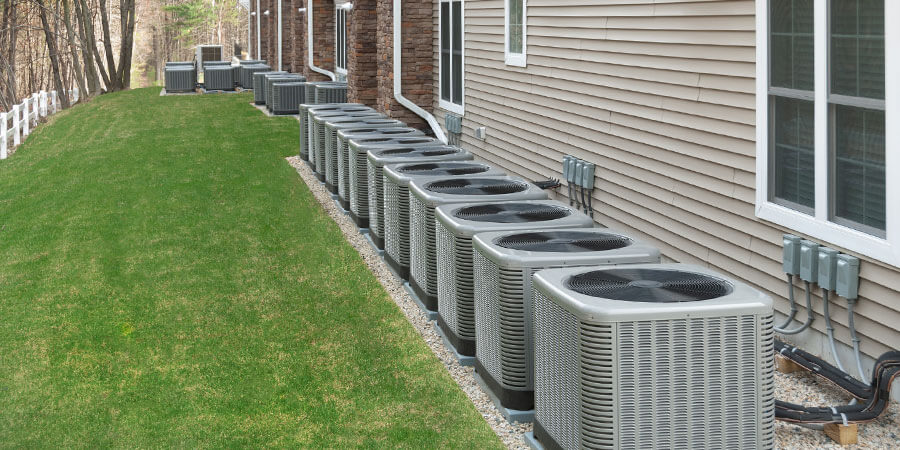 A row of air conditioners outside of an apartment complex